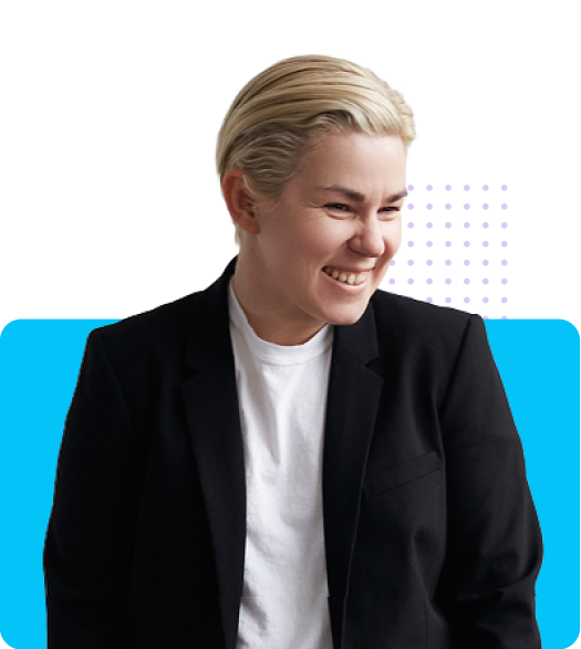 Smiling person with short blonde hair wearing a black blazer over a white shirt
